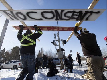 Counter-protesters tear down a blockade along the CN rail line near 231 Street and 110 Avenue, in Edmonton, Wednesday, Feb. 19, 2020.