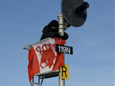 A protester puts up an upside down Canadian flag with the words RCMP Out spray painted on it, as they block the CN rail line near 213 Street and 110 Avenue, Wednesday, Feb. 19, 2020.