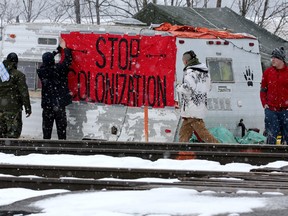 First Nations members of the Tyendinaga Mohawk Territory place a sign reading "Stop Colonization" to a camper at a blockade of train tracks servicing Via Rail, as part of a protest against British Columbia's Coastal GasLink pipeline, in Tyendinaga, Ontario, Canada February 13, 2020.