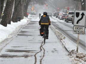 Making tracks as cyclist uses the bike lane along 83 Ave. during a brief snow fall moving through Edmonton, Feb. 4, 2020.