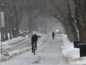 Cyclists use the bike lane along 83 Avenue as a brief snowfall moves through Edmonton on Feb. 4, 2020.