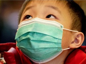 A young boy wears a face mask in public for protection against novel coronavirus.