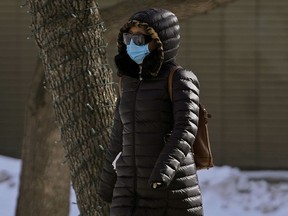 A pedestrian protects herself from COVID-19 while walking in downtown Edmonton on March 12, 2020.