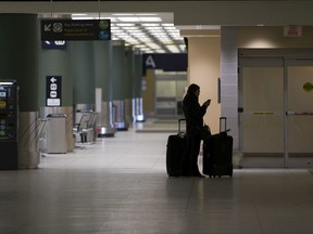 A passenger waits in the arrivals area at the Edmonton International Airport on Monday, March 16, 2020, in Edmonton.