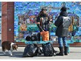 Volunteer Cameron Noyes (L) with his dog Boudica, helping out a vulnerable persons with supplies like masks, toilet paper, energy drinks, etc., along Whyte Ave. like this man at 103 St. in Edmonton, March 20, 2020.