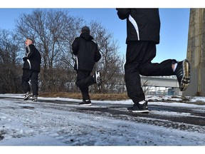 Ryan Anderson (L) running with two of the kids in a running program that he conducts here at Walterdale Park in Edmonton March 25, 2020.