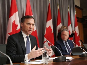 Canada's Finance Minister Bill Morneau (L) speaks during a news conference March 18, 2020 in Ottawa, Ontario, as Bank of Canada Governor Stephen Poloz looks on.