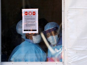 Health workers in protective gear peer from a tent which was constructed to test people for the coronavirus disease outside the Brooklyn Hospital Center in Brooklyn, New York City, U.S., March 27, 2020.