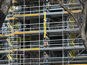 Construction workers working in unison on scaffolding, on a apartment and commerical building site underconstruction along Whyte Avenue in Edmonton on Thursday, March 19, 2020.