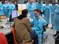 A health care worker speaks to a test patient, a staff member portraying the role of a patient to ensure the assessment systems are working, at an assessment table as they prepare for the opening of the COVID-19 Assessment Centre at Brewer Park Arena in Ottawa, during a media tour on Friday, March 13, 2020.