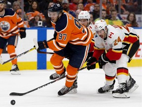 The Edmonton Oilers' Connor McDavid (97) splits the Calgary Flames' Noah Hanifin (55) and Travis Hamonic (24) during first period NHL action at Rogers Place, in Edmonton Wednesday Jan. 29, 2020. Photo by David Bloom
