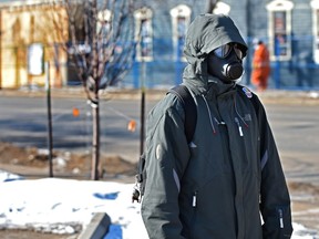 A person wearing protective mask walking in the Whyte Ave. area in Edmonton, March 20, 2020.