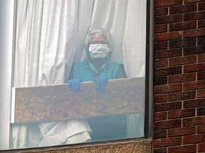 A woman looks out the window of her apartment at a seniors residence in downtown Edmonton during the COVID-19 pandemic, Sunday March 29, 2020. Citizens have been asked to self-isolate during the global COVID-19 crisis.