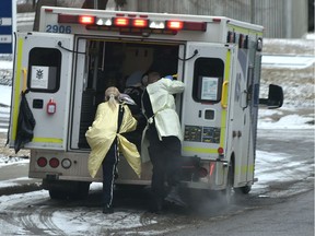 An EMS crew wearing protective gowns and masks, loading a patient into the ambulance in Edmonton, March 30, 2020.