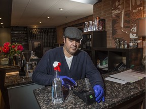 Christian Mena of Sabor, a downtown restaurant, ensures the doors, counters and debit machine are cleaned after each customer to deal with COVID-19 on Monday, March 30, 2020.