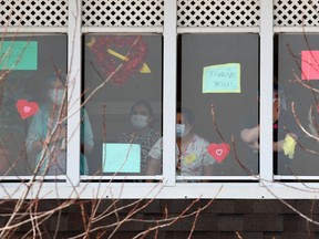 Health-care workers are seen in the window as friends and family gather outside the McKenzie Towne Continuing Care Centre. The seniors facility is Alberta's worst hit by the COVID-19 pandemic. Monday, April 13, 2020.