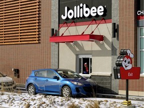 A Jolibee restaurant employee takes an order at the Edmonton restaurant's drive-thru window on March 24, 2020. Alberta Health Services has ordered the fast food restaurant in Edmonton to close due to a violation of physical distancing rules both inside and outside the restaurant during the COVID-19 pandemic.