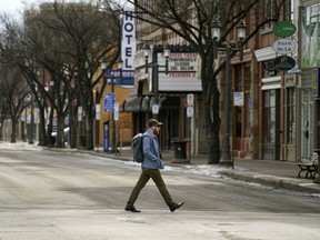 A man crosses the street in Old Strathcona on a deserted Whyte Avenue in Edmonton on Friday April 17, 2020 during the COVID-19 pandemic.