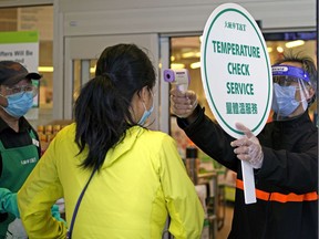 T&T Supermarket employees screen customers at the front door of the grocery store in south Edmonton on Thursday, April 23, 2020.