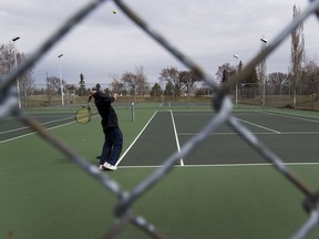 A man continues to play tennis at the Grand Trunk tennis courts after the city closed tennis courts, pickleball courts, basketball courts, volleyball courts, disc golf and premier sports fields due to the COVID-19 pandemic on Monday, April 27, 2020 in Edmonton.  There were no signs at the court to indicate the closure.