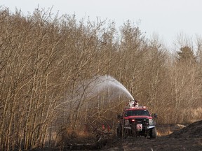 Edmonton Fire Rescue Services firefighters put out a grass fire along the train tracks along Hermitage Road near Hooke Road in Edmonton, on Tuesday, April 28, 2020.