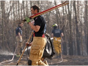 Edmonton Fire Rescue Services firefighters put out a grass fire along the train tracks along Hermitage Road near Hooke Road in Edmonton, on Tuesday, April 28, 2020.
