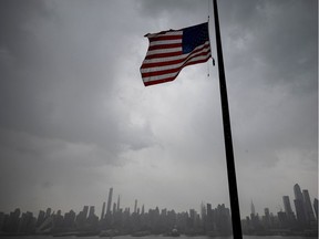 An US flag flies at half-mast half mast in front of the Skyline of Manhattan of New York City seen from Weehawken, New Jersey, on April 21, 2020. (