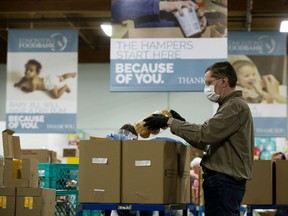 A volunteer packs hampers at the Edmonton Food Bank, 11508 120 St., Tuesday April 28, 2020. The organization has had to make changes to the way food hampers are processed in the wake of the COVID-19 pandemic.