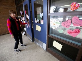 Grade 5 teacher Kathleen Eistetter looks at paper hearts and messages left for teachers and staff, on the front door of St. Mary Catholic School, in Edmonton Wednesday April 1, 2020.
