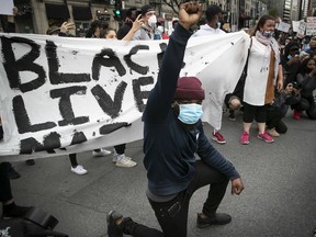 A protester takes a knee during Sunday's demonstration against racism and police brutality in Montreal on Sunday, May 31, 2020.