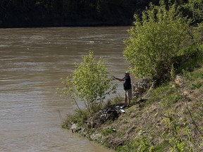 Andy (no last name given) casts a line while fishing along the North Saskatchewan River, in Edmonton Sunday May 24, 2020. On Friday the City warned residents to stay away from the rapidly-rising water of the North Saskatchewan River. Photo by David Bloom