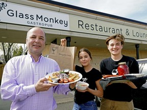 Rob Filipchuk, owner of the Glass Monkey Gastropub in southwest Edmonton, and his children Layla and Noah, holds a plate of the Ukrainian Feast, one of the themed meals that is available for pick-up at his restaurant.