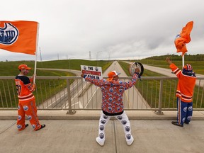 Edmonton Oilers superfan Blair Gladue (centre), his brother Clayton Cardinal (right) and his nephew Brody Gladue cheered from the bridge at St. Albert Trail and Anthony Henday Drive after hearing about the resumption of the NHL playoffs in Edmonton, on Tuesday, May 26, 2020.