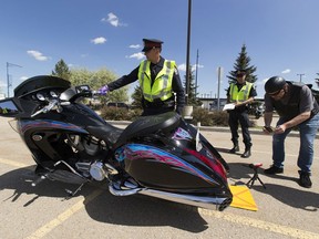 Cst. Trevor Henderson of the Edmonton Police Service's traffic section tests the noise level of Al Horne's bike while Horne records the level with his phones camera on Thursday, May 28, 2020  in Edmonton.  Motorcyclists with loud engines had the chance for their bikes to get tested during an amnesty event Thursday afternoon