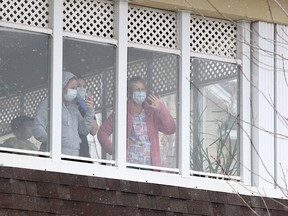 Residents and staff members wave at supporters gathered outside the McKenzie Towne Continuing Care Centre on Friday, April 3, 2020.