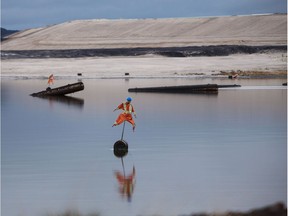 Scarecrows, used to deter birds from landing, stand in the Syncrude Canada Ltd. tailings pond in the Athabasca Oil Sands near Fort McMurray on Sunday, Sept. 9, 2018.