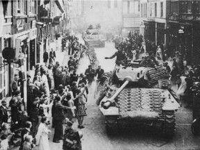 Dutch people line the street to greet Canadian soldiers as they parade down a street after the liberation of the Netherlands in 1945.