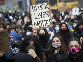 Protesters hold up sign during anti-racist and anti-police brutality demonstration in Montreal on Sunday May 31, 2020. Most protesters are wearing a mask because of the COVID-19 pandemic.