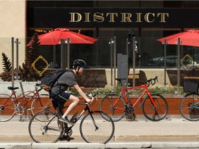 A cylist rides along the protected bike lane at 109 Street and 100 Avenue past parked bicycles at District Cafe and Bakery in Edmonton. File photo.
