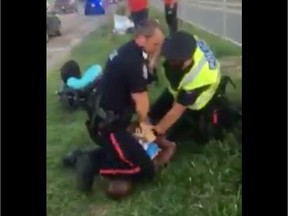 An Edmonton police officer places his knee on a  man's head and neck during an arrest in July 2018.