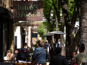 Diners are passed by walkers at Julio's Barrio on Whyte Avenue in Edmonton, on Tuesday, June 9, 2020. The Alberta government has announced that the province will begin Phase 2 of COVID-19 re-opening.