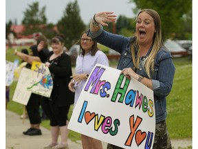 St. Mary Catholic Elementary School assistant principal Lauren Hawes, right, waves goodbye to students and parents during a drive-by year-end farewell parade in front of the school during the COVID-19 pandemic on Friday, June 26, 2020.