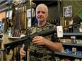 Jim Osadczuk, of Sebarms Guns and Gear, holds an AR-15 variant rifle at his shop in Edmonton on May 2, 2020. The government of Canada banned the import, sale and purchase of this gun and other military-style assault weapons in the country on May 1, 2020.