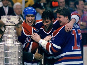 Left to right, Edmonton Oilers veterans team captain Mark Messier, Asst. captain Kevin Lowe, and Jari Kurri share the joy of them all winning their fifth Stanley Cup championship together. NHL commissioner John Ziegler reaches in to shake their hands and then hand over the cup to Messier after the Oilers beat the Boston Bruins in five games on May 24, 1990.