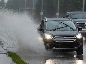 A driver splashes through a large puddle formed after a day of rain along 112 Avenue near Borden Park in Edmonton, on Tuesday, June 30, 2020. Photo by Ian Kucerak/Postmedia
