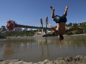 Jaimen Williams backflips into the North Saskatchewan River from Accidental Beach, in Edmonton Monday July 27, 2020. The under construction Tawatinâ Bridge is visible in the background. Photo by David Bloom