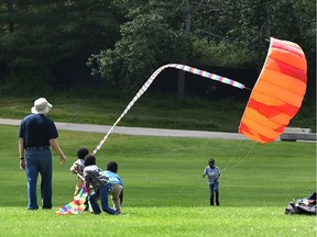 Children having fun pulling on the tail of a kite flyer at Hawrelak Park in Edmonton, July 5, 2020.