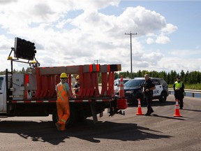 City of Edmonton crews set up a roadblock at Ellerslie Road and 17 Street as Edmonton Police Service officers undertake a multi-hour investigation of a serious crash in Edmonton on Saturday, July 18, 2020.
