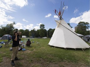 Organizer Austin Mihkwaw talks on his phone at a camp set up west of Remax Field in a parking lot on Friday, July 24, 2020 in Edmonton. The camp has been set up to give food and water to homeless residents.