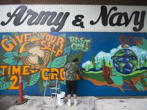 Evan, also known as Rast, works on a mural on the boarded up exterior of the Army and Navy Department Store, in Edmonton Monday July 6, 2020. The store permanently closed in May due to financial challenges associated with the COVID-19 pandemic. Evan is one of two artists contracted to cover the approximately 90 foot long and 10 foot high front facade of the building.